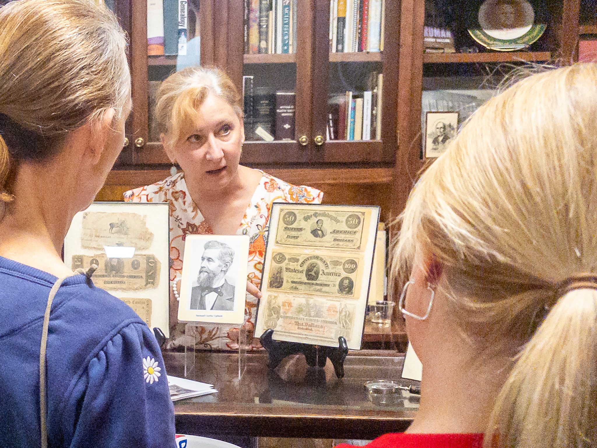 PHOTO BY MEGAN JANTOS
Weston Historical Museum
curator Shelly Franklin Weinfurt
displays examples of Confederate
currency and a portrait of
Samuel Curtis Upham during
History Mystery Hour on Aug.
20. Upham sold facsimile
notes as Civil War souvenirs,
but some were trimmed and
passed as currency in the
South.